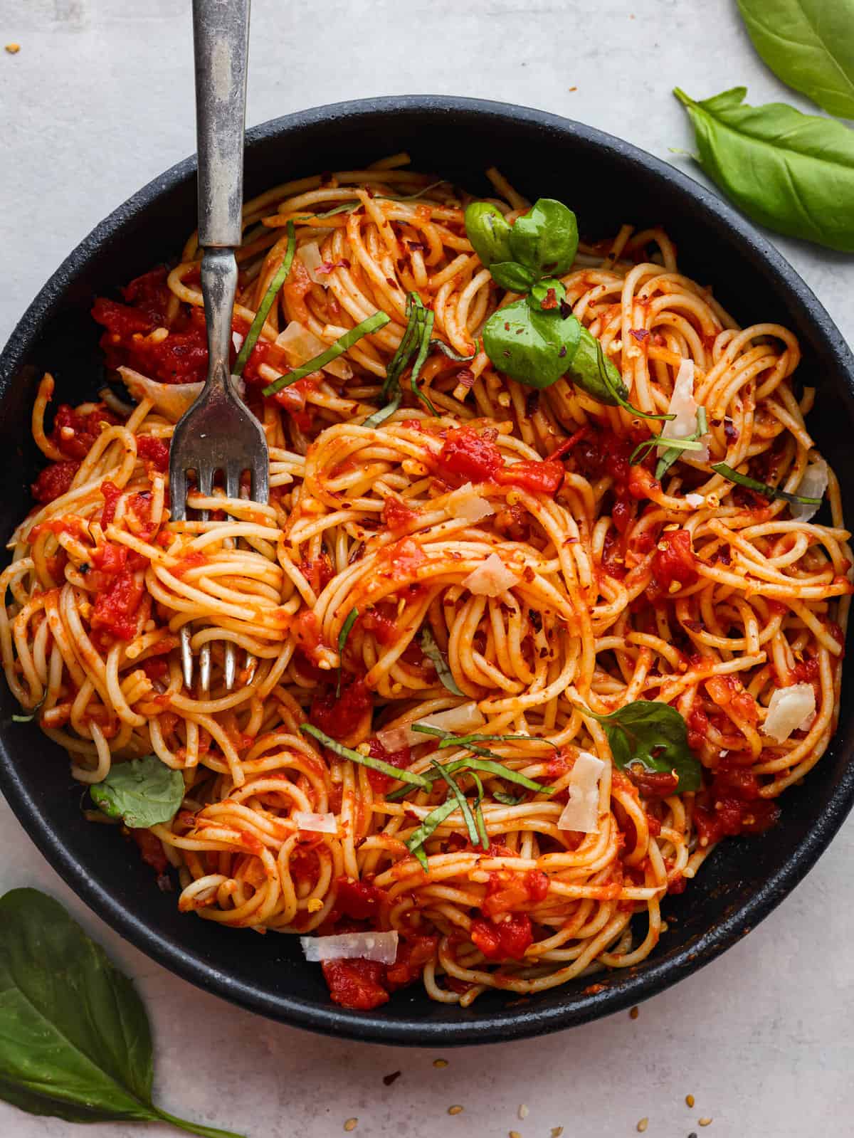 a very tasty bowl of spaghetti covered in a chunky pomodoro (tomato) sauce topped with basil